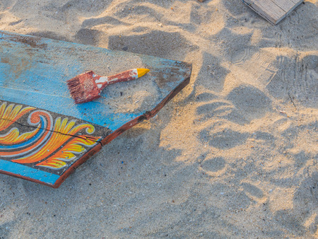 Dirty paint brush on wooden piece and sand background.の写真素材
