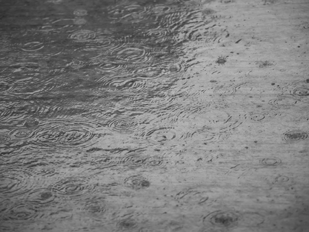 Rainy day with rain drops on the cement floor makes circles shape on the water surface.の写真素材