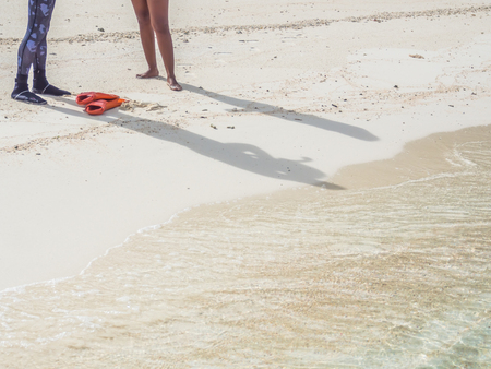 The man and woman are standing on the beach with clean sand and clear sea.の写真素材