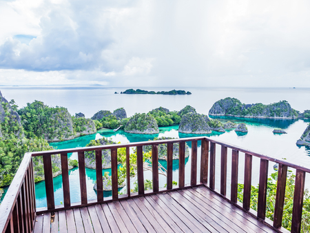 Brown wooden balcony with landscape background of wonderful islands shape and clear turquoise sea or lagoon in cloudy day. の写真素材