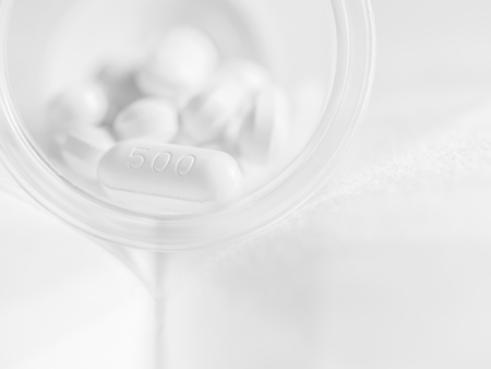 Paracetamol tablets in plastic glass on gray fabrics background