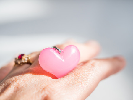 Closeup of pink heart shape, blurry rink and woman 's fingers. Concepts and ideas for love.の写真素材