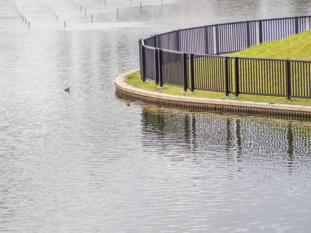 Metal fence and lake in the parkの写真素材