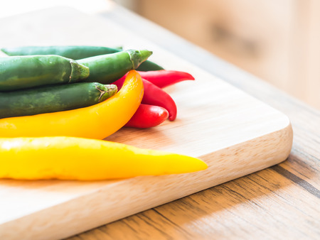 Green, red and yellow chili pepper on wooden cutting board. Preparing and cooking concepts.の写真素材