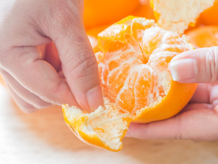 Peeling oranges, preparing for eating. Closeup of oranges with woman 's hand.の写真素材