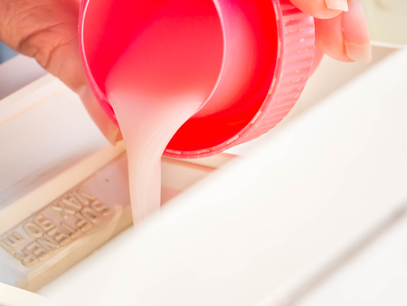 Woman flow fabric softener in the cap to washing machine container for laundry processing. の写真素材