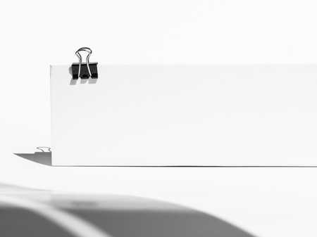 Close-up of black paper clip holding a blank folding paper sheetの写真素材