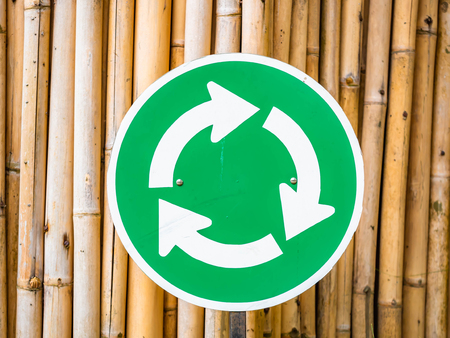 Green roundabout traffic signs on dry bamboo wall.の写真素材
