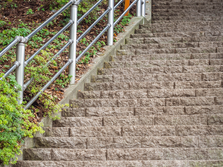 Rock stairs with fence and green plants in the park.