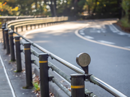 Closeup of street light and fence with the curve road, pavement and forest in the park.の写真素材