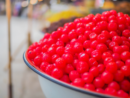 Closeup of Asian red fruit compote in white bowl with blurry street food local market.の写真素材