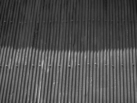 Abstract black and white tone background of vertical striped and horizontal dots pattern of old aluminium zinc wall texture with light and shadow sunlight effect.の写真素材