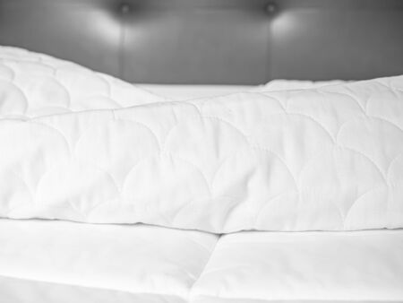 Crumpled and wrinkle white bed cover on bed topper in the bedroom. Housework preparation before laundry process.の写真素材