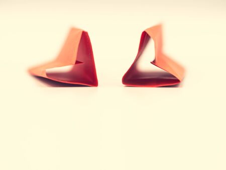 Crossed process tone. Closeup of folded paper vivid or vibrant red hearts shape on pastel yellow color background. Valentine 's day, wedding, love, sweet and romance concepts and ideas.の写真素材