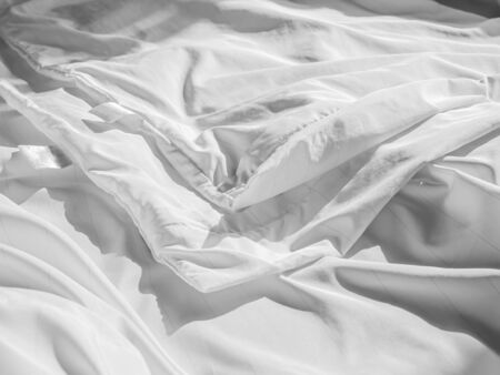 Abstract black and white tone of zippered dust mites pillow cover on wrinkle white bed cover sheet on the bed in the bedroom. Housework preparation before or after laundry process.の写真素材