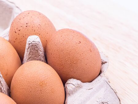 Closeup of water drops from condensation reaction on chicken brown eggs in paper carton tray and...