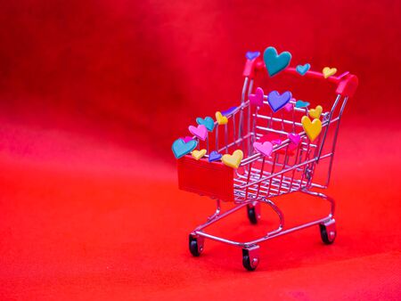 Closeup of heart shape stickers on shopping cart with blurry vivid, vibrant red background for Love, romance, shopping, business, greeting card concept and idea.の写真素材