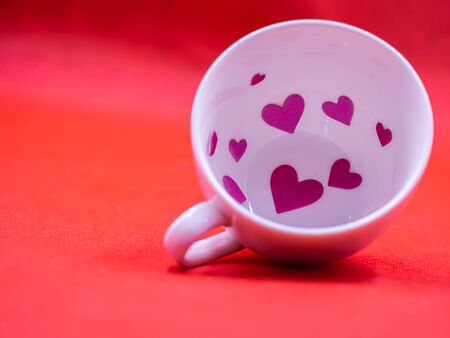 Closeup of white coffee cup and pink paper sticker on vivid or vibrant red background for love, valentine, romance, wedding, greeting card concept and idea.の写真素材