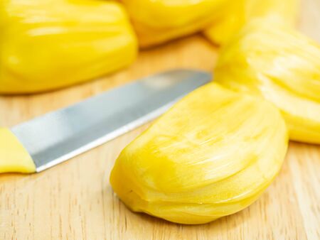 Closeup of yellow ripe jackfruit and knife on wooden cutting board in the kitchen or restaurant.
