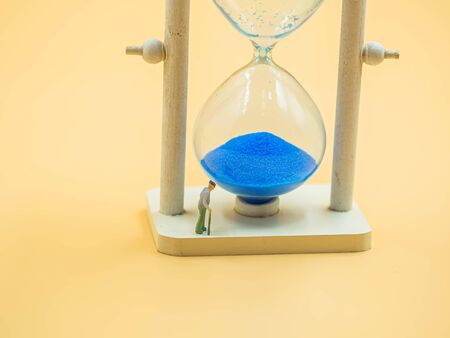 Sand glass and miniature figure of elder man  with blurry golden color background for life stages...