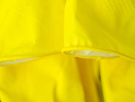 Abstract and closeup of vivid, vibrant yellow color rubber glove, stripe, line pattern, rough texture and gradient backgroundの写真素材