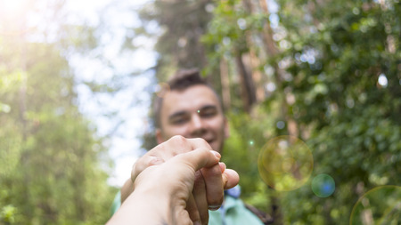 The young man pulls the girl's hand on the forest pathの写真素材