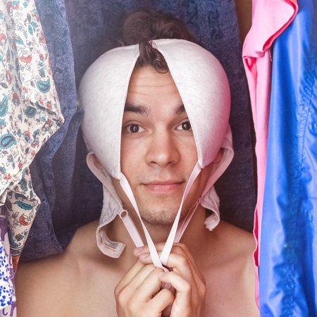 A young man hiding in the closet among women's clothing. Lover in the closet.の写真素材