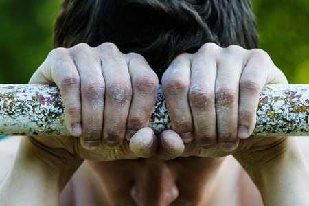 young man holding hands on the horizontal bar