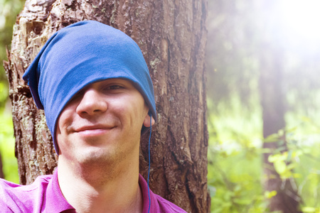 A young man sits under a tree and listens to musicの写真素材