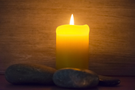 A candle is lit and surrounded by stones.の写真素材