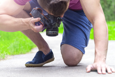 Young man taking pictures of something on the pavementの写真素材
