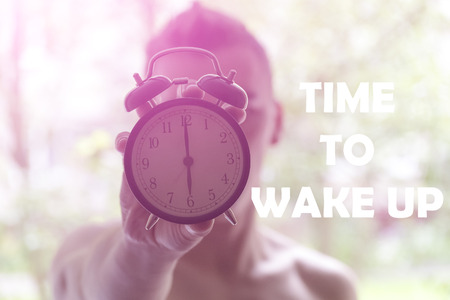 A young man holding a clock. The concept of active in the morning. Awakening.の写真素材