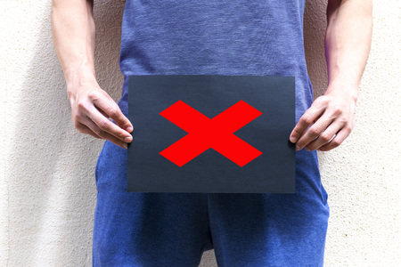 A young man holds a placard at the level of the genitalsの写真素材