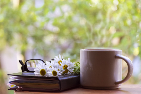 Mug, daisies, Notepad, glasses. The concept of a Sunny summer morning.の写真素材