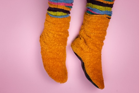 Female feet in orange socks on a pink background.の写真素材