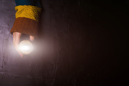 Male hand holds out a candle on a black backgroundの写真素材