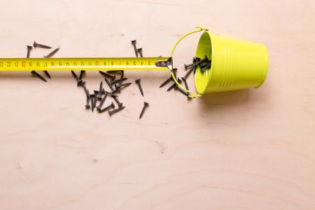 Roulette measuring pulling a bucket of nails. Still life.の写真素材