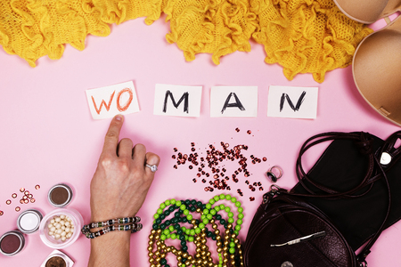 Man in women's jewelry puts the inscription on pink backgroundの写真素材