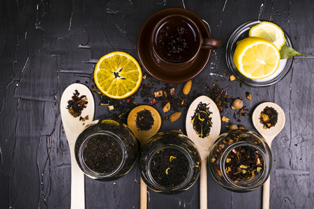 A variety of teas, spices and fruits on dark textured background.の写真素材
