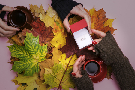 A man gives a ring on the girl on the background of autumn leaves.の写真素材
