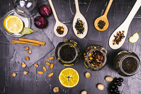 Teas in cans and wooden spoons surrounded by fruit and nutの写真素材