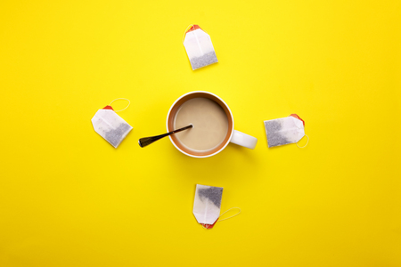 Cup with coffee and tea bags around on a colored backgroundの写真素材