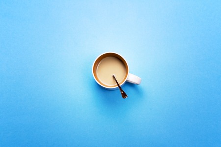 A Cup with coffee and spoon on a colored background. The concept of coffee breaksの写真素材