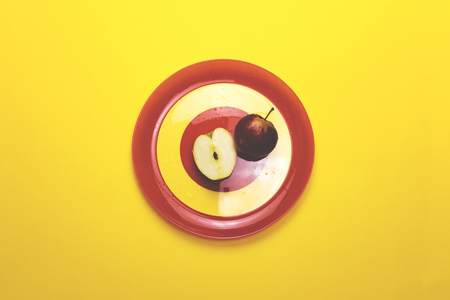 Apple on a red plate on a colored backgroundの写真素材