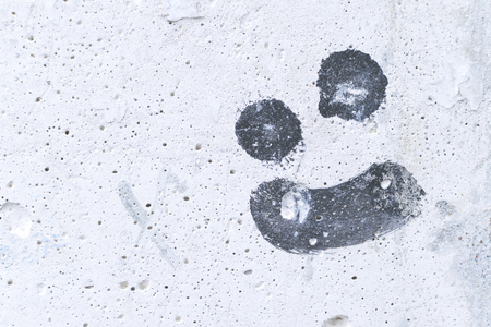 Drawing a malicious smile on white concrete wall.の写真素材
