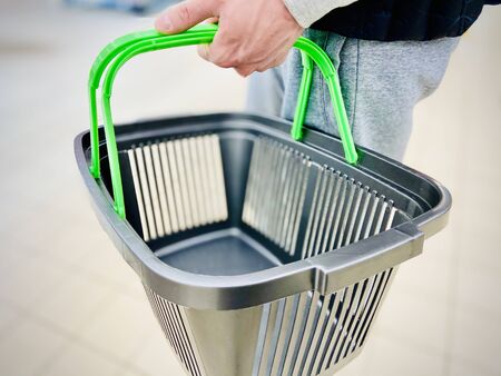 A man holds a grocery basket in a supermarket. A close-up. Mobile photoの写真素材
