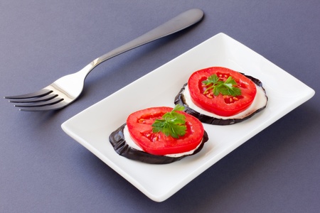 Cooked eggplant with fresh tomato dressed with mayonnaise and garlic on dark backgroundの写真素材