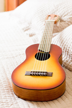 Acoustic guitalele lies on the bed