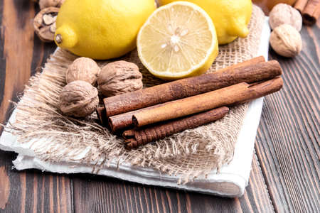 Lemon cinnamon sticks and nuts wooden background
