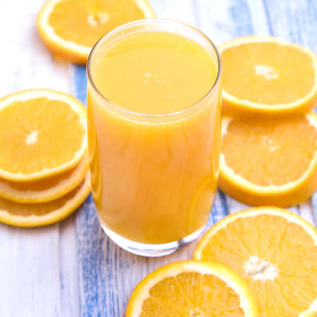 Glass of freshly pressed orange juice with sliced orange half on wooden tableの写真素材